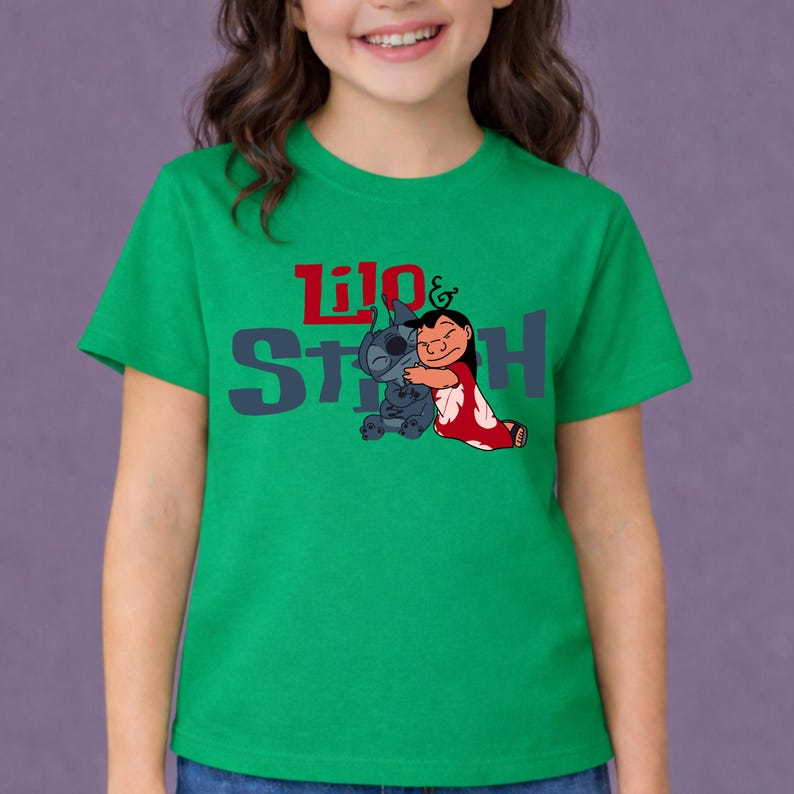 K&ouml;nnte beinhalten: Ein leuchtend gr&uuml;nes Kurzarm-T-Shirt mit einer Grafik der sich umarmenden Figuren Lilo und Stitch. Der Schriftzug Lilo & Stitch ist in Rot und Dunkelgrau auf der Brust aufgedruckt, wobei die Figuren unter dem Wort Lilo platziert sind.