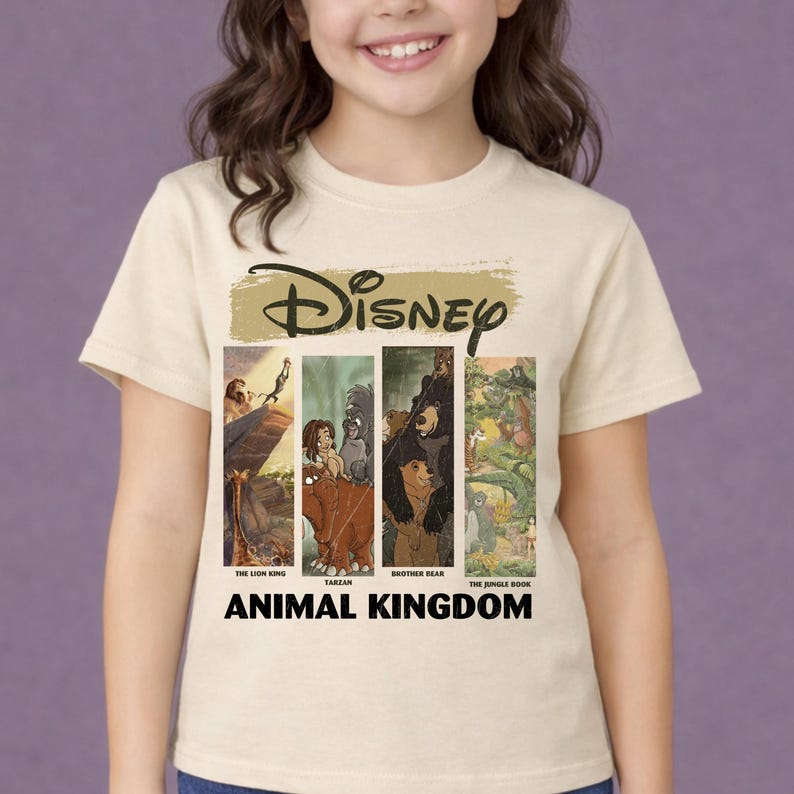 Peut inclure: T-shirt cr&egrave;me avec le logo Disney et des images de "Le Roi Lion", "Tarzan", "Fr&egrave;re des ours" et "Le Livre de la Jungle". Les mots "Animal Kingdom" sont imprim&eacute;s en noir en dessous.