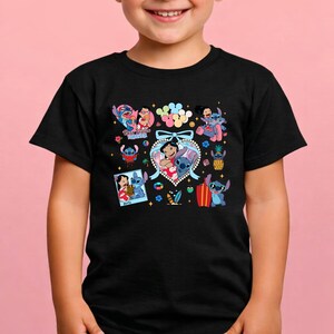 May include: A black short-sleeved t-shirt featuring a colorful graphic print of Lilo and Stitch. The design includes multiple illustrations of the characters, a heart-shaped frame with a blue bow, a pineapple, a surfboard, and the text Best Friends Forever.