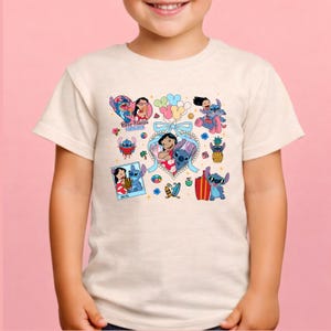 May include: A cream-colored short-sleeve t-shirt featuring a colorful graphic print of Lilo and Stitch characters. The design includes multiple illustrations of the pair, a heart-shaped frame with a light blue bow, and the text Best Friends Forever.