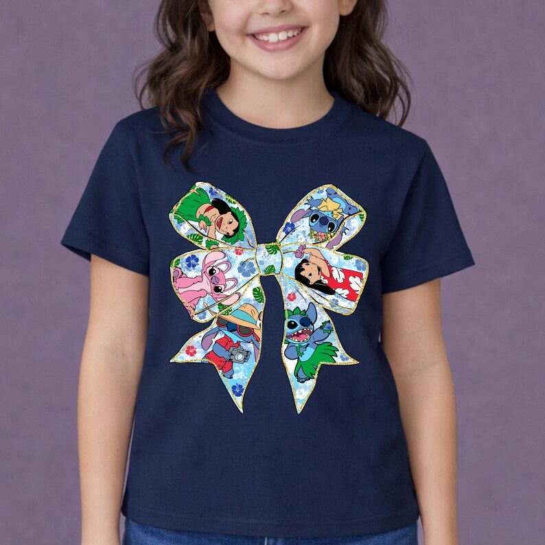 May include: A navy blue t-shirt with a large bow design featuring cartoon characters. The bow has floral patterns and gold trim. Characters include Stitch and others from the Lilo & Stitch franchise. The t-shirt is worn by a child.