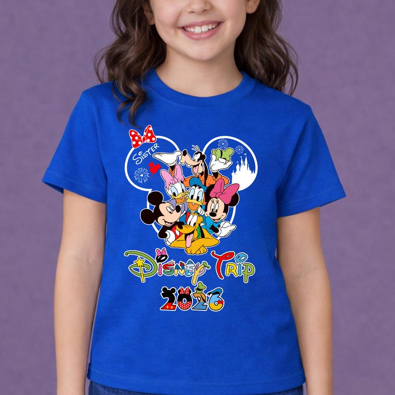 May include: A blue t-shirt with a vibrant graphic of Disney characters such as Mickey and Minnie Mouse, Donald and Daisy Duck, Goofy, and Pluto. The shirt displays the text "Disney Trip 2020" and "Sister" within a Mickey Mouse ear design.
