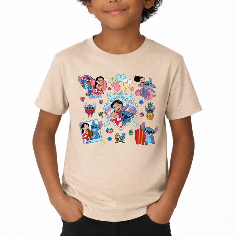 May include: A beige short-sleeve t-shirt featuring a colorful graphic print of Lilo and Stitch characters. The design includes multiple illustrations of the pair, a heart-shaped frame with a blue bow, balloons, and the text Best Friends Forever.