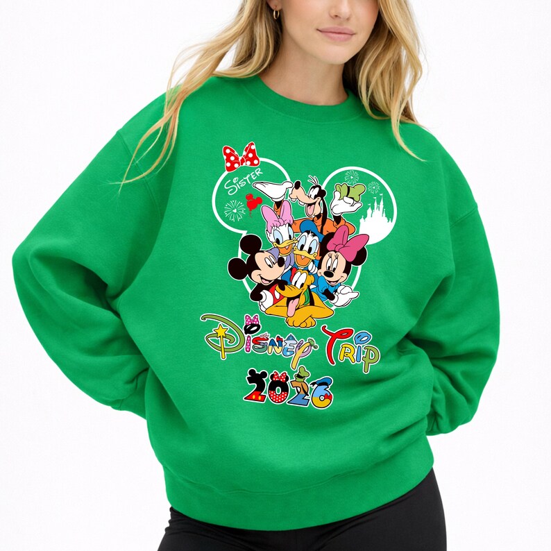 May include: Green sweatshirt with a Disney Trip 2023 graphic featuring Mickey Mouse, Minnie Mouse, Donald Duck, Daisy Duck, Goofy, and Pluto. The word "Sister" is above the characters. The sweatshirt is a solid green colour.