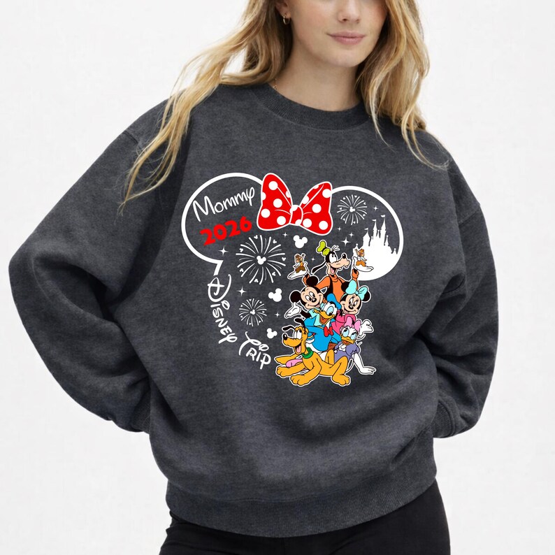 May include: Dark gray sweatshirt featuring a graphic of Mickey Mouse ears with a red polka dot bow. The text "Mommy 2026 Disney Trip" is printed above a group of Disney characters, including Mickey, Minnie, Donald, and Goofy.