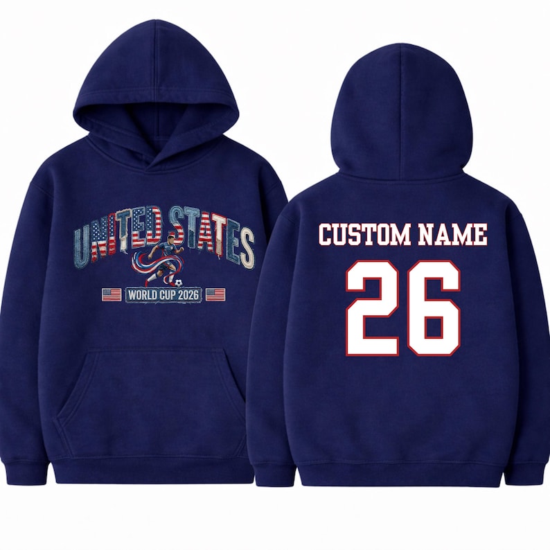 Peut inclure: Sweat-shirt &agrave; capuche bleu marine avec l'inscription "UNITED STATES", un graphisme de joueur de football et le texte "WORLD CUP 2026". Le dos affiche "CUSTOM NAME" et le num&eacute;ro "26" en blanc avec une bordure rouge.
