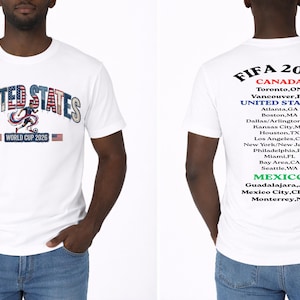 Peut inclure: T-shirt blanc avec l'inscription "UNITED STATES" dans un design patriotique et le texte "WORLD CUP 2026". Le dos du t-shirt liste les villes h&ocirc;tes au Canada, aux &Eacute;tats-Unis et au Mexique pour la Coupe du Monde de la FIFA 2026.