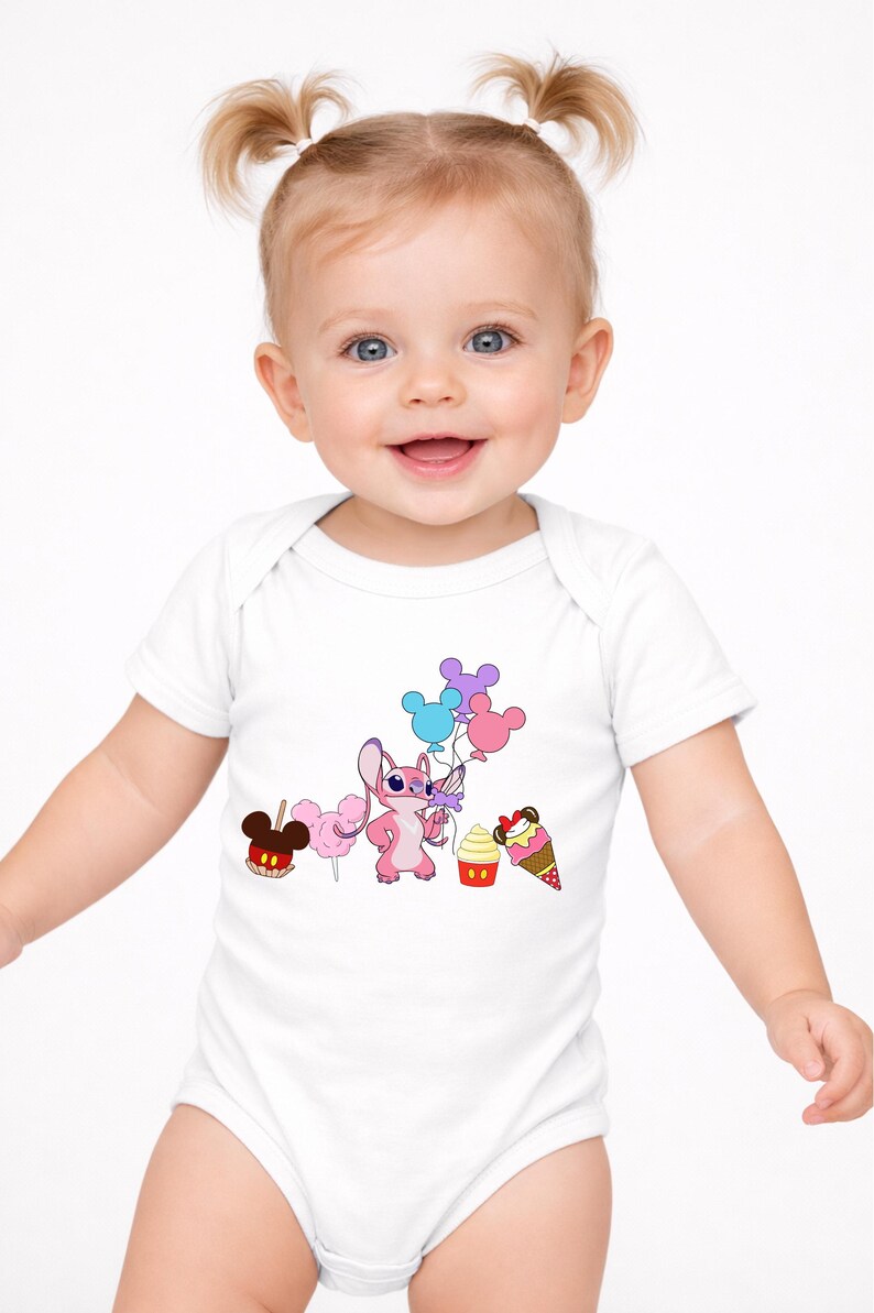 Op de afbeelding: Witte babybody met een roze stripfiguur met ballonnen, samen met een Mickey Mouse-vormige appel, suikerspin, een cupcake en een ijsje. De baby lacht en heeft blonde staartjes.