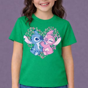 以下が含まれることがあります： 緑色のTシャツ。ディズニー映画「リロ＆スティッチ」のキャラクター、スティッチとエンジェルのグラフィックが特徴です。キャラクターはハート型に描かれ、背景には小さなハートが散りばめられています。子供向けのデザインです。