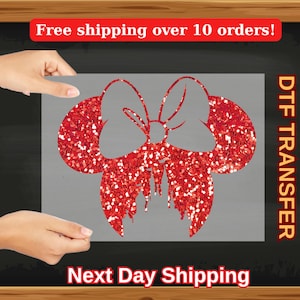 May include: Red glitter iron-on transfer design of a bow with two ears, perfect for creating custom apparel or accessories. DTF Transfer.