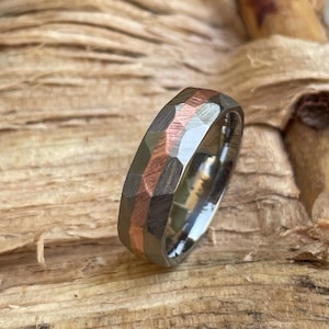 May include: A hammered titanium wedding band with a copper inlay. The band has a brushed finish and a slightly rounded profile.