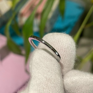 May include: A thin silver band ring.
