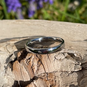 May include: A simple silver band ring with a polished finish.