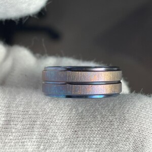 May include: A blue and brown metal ring with a brushed finish and two grooves.