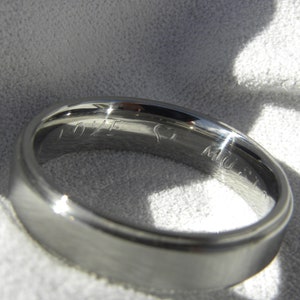 May include: A silver wedding band with the inscription "LOVE" and a heart symbol on the inside of the band.