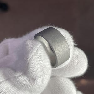 May include: A grey metal ring with a brushed finish. The ring is thick and has a rounded edge.