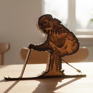 May include: A wooden sculpture of a skier in a downhill position. The sculpture is made of layered wood, with details of a ski lift, trees, and other skiers. The sculpture is brown and tan, and sits on a wooden table.