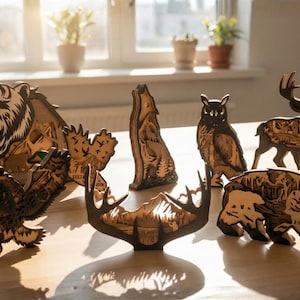May include: Wooden animal figurines, including a bear, wolf, owl, deer, and eagle, are displayed on a wooden surface. The figurines are intricately cut and feature detailed designs. The bear is roaring, and the wolf is howling.