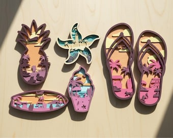 May include: A collection of layered wooden beach-themed decorations, including a pineapple, starfish, ice cream, surfboard, and flip-flops. Each piece features a layered design with beach scenes in shades of pink, orange, and blue, with a dark purple outline.