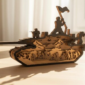 May include: A wooden tank model with intricate cut-out details. The model features soldiers, a flag, and a detailed interior. The tank is made of light brown wood with dark brown accents, and is displayed on a wooden surface.