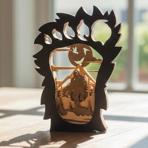 May include: A wooden laser-cut art piece featuring a bear paw silhouette frame. Inside, a layered scene depicts a mountain range, trees, a full moon, and a Bigfoot figure. The piece is made of light and dark brown wood.