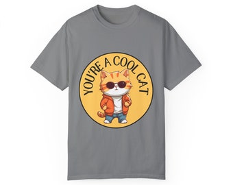 May include: Gray t-shirt with a yellow circle graphic featuring a cartoon cat wearing sunglasses and a red jacket. The text "YOU'RE A COOL CAT" is written around the circle.
