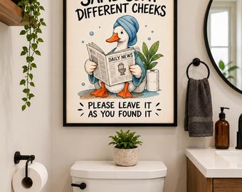 May include: A framed wall art print featuring a cartoon duck wearing a blue towel on its head, reading a newspaper titled Daily News, with the text Same Seat Different Cheeks and Please Leave It As You Found It in black lettering.