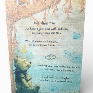 Może przedstawiać: Karta A5 z kości słoniowej z lnu z ilustracją misia, motyli i drzewa. Karta zawiera tekst "We Miss You" i wzruszającą wiadomość. Możliwość personalizacji.