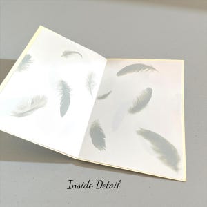 May include: Open greeting card with a soft yellow border, revealing a white interior adorned with delicate gray feather illustrations. The text "Inside Detail" is printed at the bottom of the card.