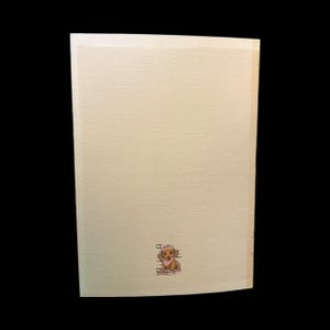 May include: A light beige wooden sign with a small illustration of a dachshund wearing a hat and scarf. The sign has a textured surface and a simple, clean design. The dog illustration is in shades of brown and tan.