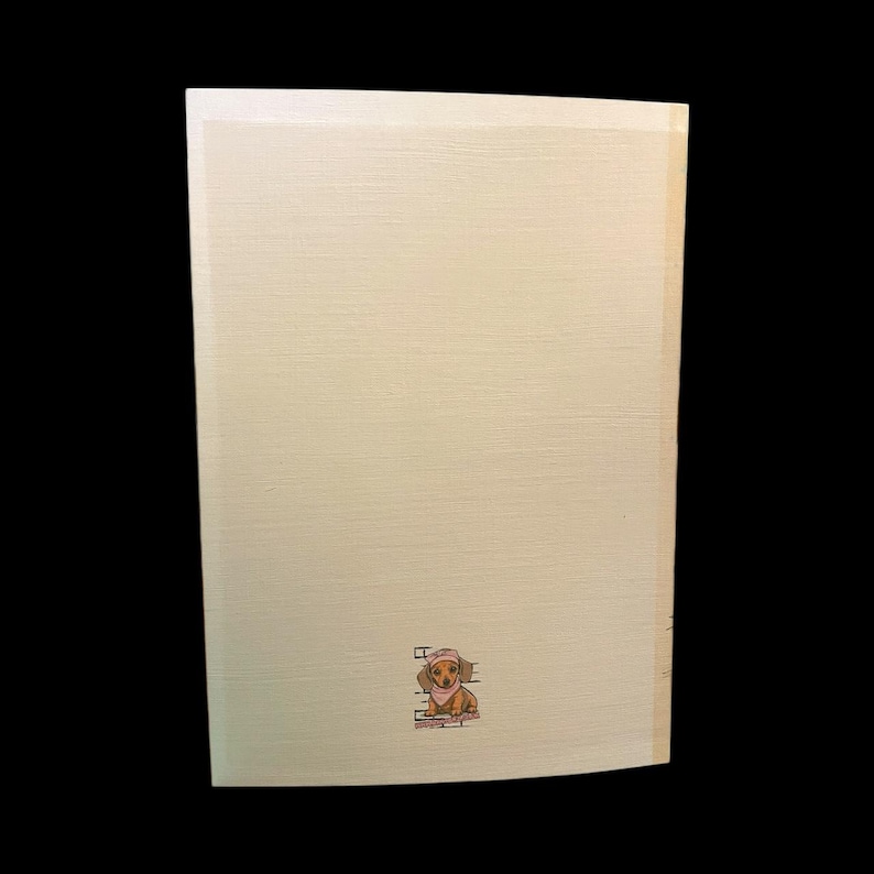 May include: A light beige wooden sign with a small illustration of a dachshund wearing a hat and scarf. The sign has a textured surface and a simple, clean design. The dog illustration is in shades of brown and tan.