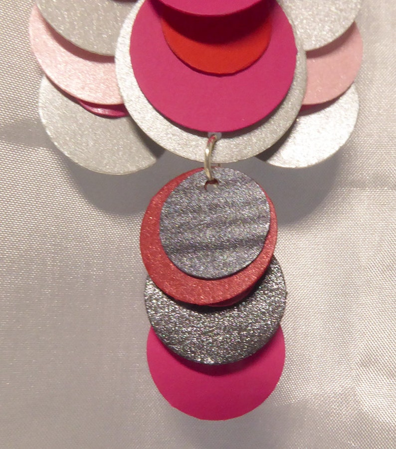 May include: Silver, pink, and red layered circle earrings with a sparkly silver and red dangle.