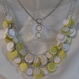 May include: A silver chain necklace with multiple layers of layered circles in shades of white and yellow.