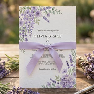 May include: A wedding invitation with floral watercolor designs in shades of purple and green. The invitation is tied with a lavender ribbon. The text reads "Olivia Grace & Aley" and includes the wedding date and time.