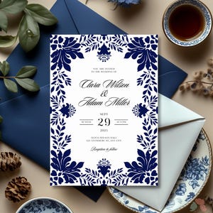 May include: A white wedding invitation with a blue floral border. The invitation reads "You are invited to the wedding of Clara Wilson & Adam Miller, Sunday, Sept 29, 2025 at 4 PM, Olivia Wilson Hall, 123 Anywhere St, Any City, Reception to follow."