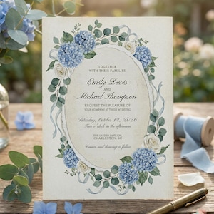 May include: Wedding invitation featuring an oval design with blue hydrangea and white rose floral accents. The invitation includes the names Emily Davis and Michael Thompson, along with the wedding date and location.
