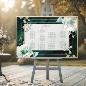 May include: A framed seating chart with a dark green background and gold trim, displayed on a wooden easel. The chart features white floral accents and guest names. The text "September 22" is visible.
