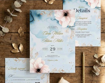 May include: Wedding invitation suite featuring a light blue watercolor background with pink floral accents and gold script. The suite includes an invitation, details card, and RSVP card. A gold pen and ribbon are also present.
