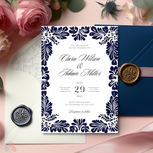 May include: A white wedding invitation with a navy blue border featuring a floral design. The invitation reads "You are invited to the wedding of Clara Wilson & Adam Miller, Sunday, Sept 29, 2025 at 4 PM, Olivia Wilson Hall, 123 Anywhere St, Any City, Reception to follow."