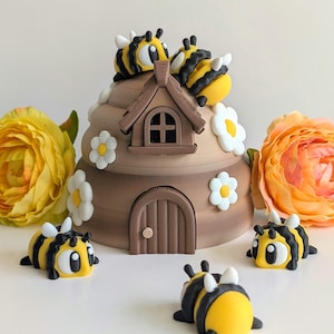 May include: A brown, dome-shaped beehive structure with a small door and window, decorated with white flowers. Two bees are perched on top, and three additional bees are positioned around the base of the hive on a white surface.