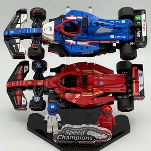May include: Two Lego Speed Champions race cars on display stands. The top car is blue, white, and red with the logos "VISA", "Cash App", and "ORLEN". The bottom car is red with the logos "Santander", "HP", and "Shell".