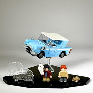 Puede incluir: Un set de Lego con un coche azul claro con techo blanco y tres minifiguras. El set incluye un letrero en forma de nube que dice "-76424 165 piezas". También se incluye una pequeña rata marrón y un búho blanco.