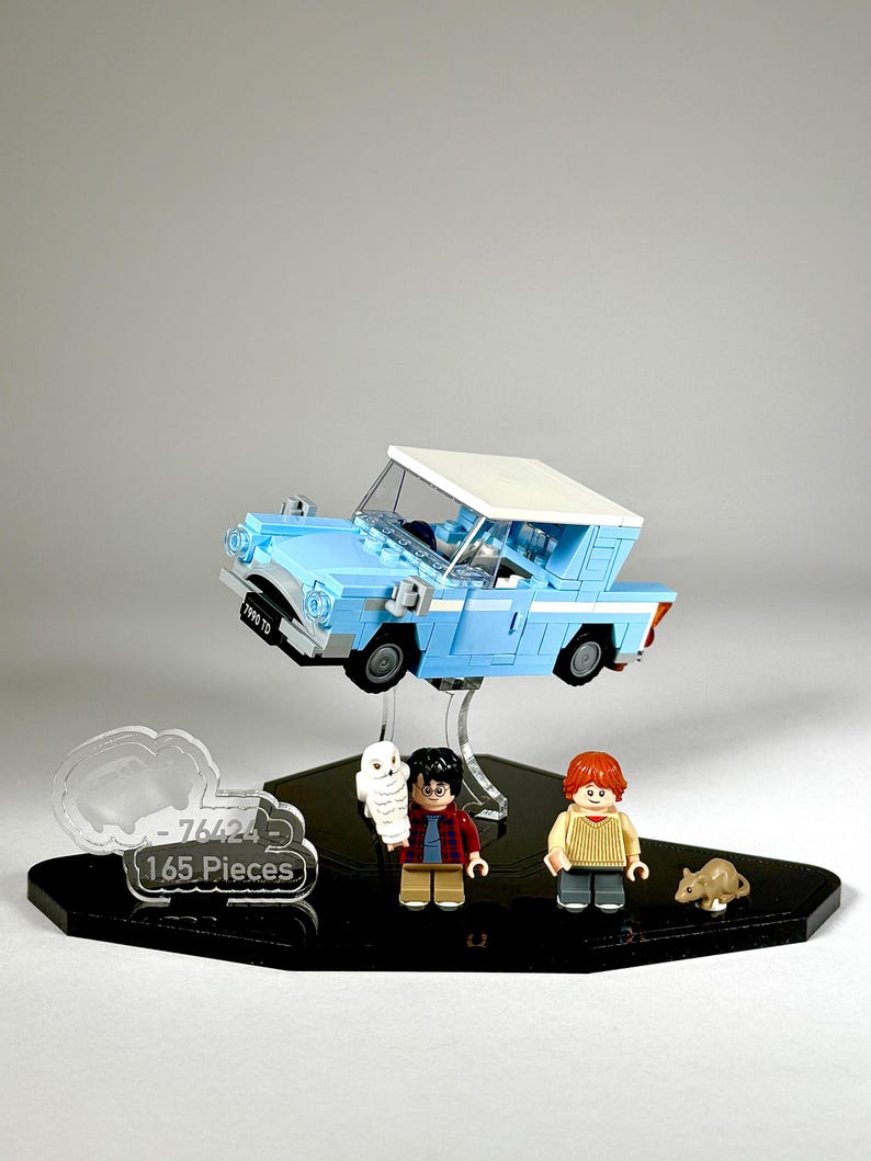 May include: A Lego set featuring a light blue car with a white roof, and three minifigures. The set includes a cloud-shaped sign that reads "-76424 165 Pieces". A small brown rat and a white owl are also included.
