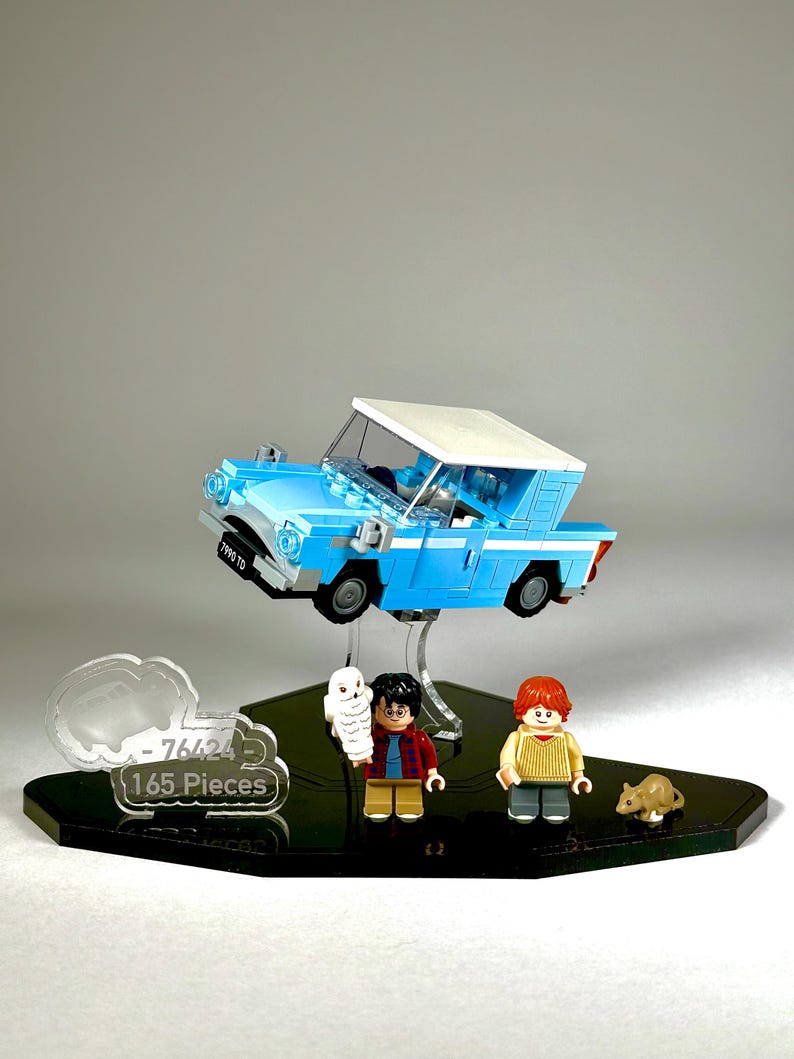 May include: A Lego set featuring a light blue flying car with a white roof, and miniature figures of Harry Potter, Ron Weasley, and Hedwig the owl. The set includes a black base with the text "76424 165 Pieces".