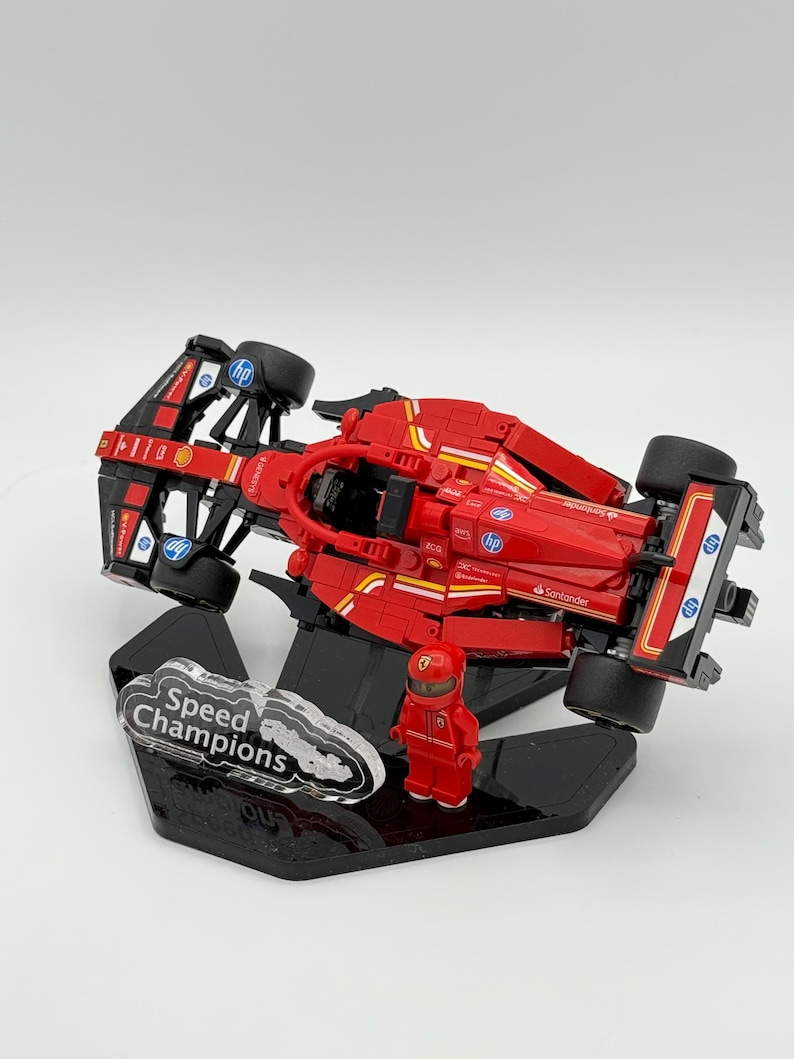 May include: A red Lego Speed Champions Ferrari Formula 1 race car with a black and white driver figure on a black display stand. The car has the logos of Santander, HP, and Shell on the side.