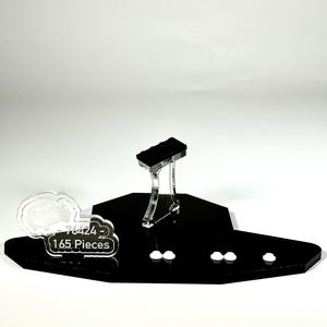 May include: A black display stand with a clear support structure holding a black rectangular object. The stand has a unique shape and includes the text "76424 - 165 Pieces" on a white cloud-shaped element. Several small white cloud-shaped elements are also present.