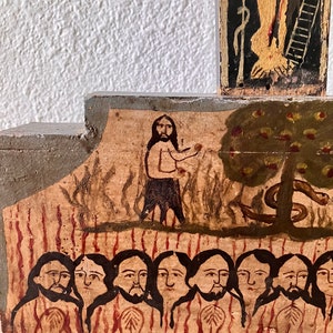 May include: A section of a painted wooden religious icon depicting biblical scenes. The artwork features figures with long hair and beards, a tree with apples, and a serpent. The color palette includes earth tones, red, and black.