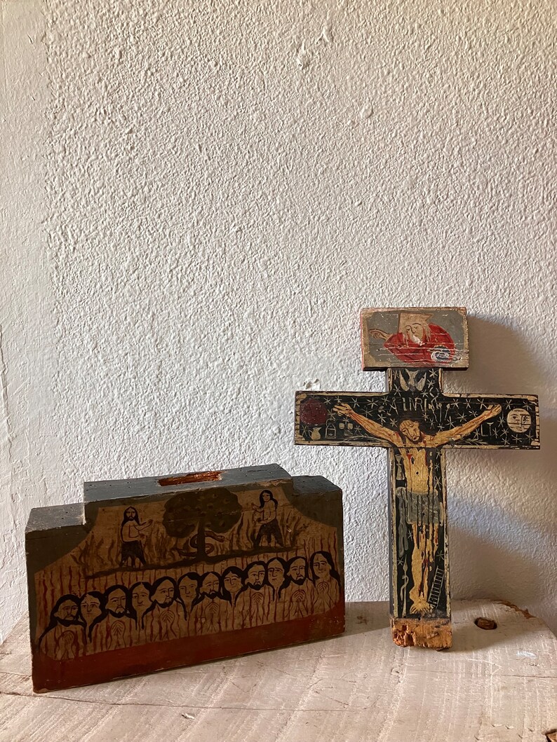 May include: Two hand-painted wooden religious items. One is a cross with a figure of Jesus, the other is a rectangular block with a painted scene of figures. Both items have a rustic, aged appearance.