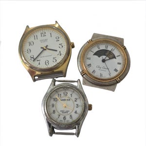 May include: Three vintage wristwatches with white faces and various metal bands. One watch has a gold-tone case with the word "SHARP" on the face. Another watch has a silver and gold-tone case with a moon phase design. The third watch is silver with the text "watch-it".