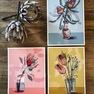 May include: Four different floral prints featuring various types of flowers in vases. The prints are on a light pink, light blue, yellow, and white background.